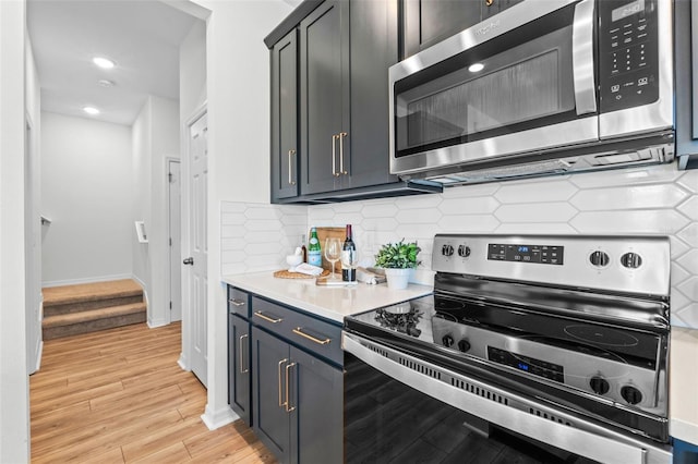 kitchen with recessed lighting, light countertops, tasteful backsplash, light wood finished floors, and stainless steel appliances
