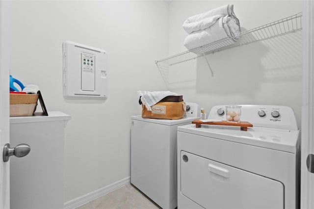 clothes washing area with independent washer and dryer, light tile patterned floors, laundry area, and baseboards