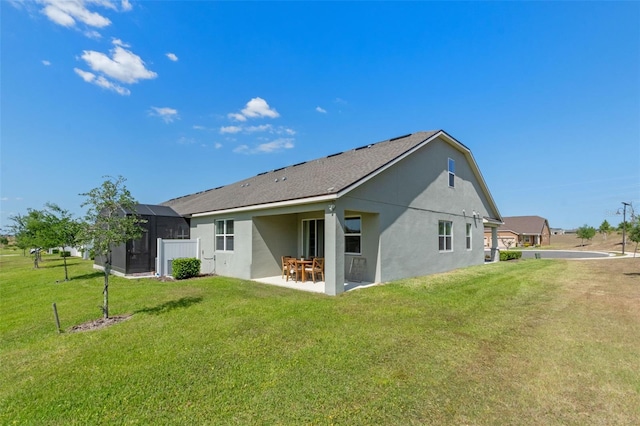 back of property with a patio, stucco siding, a yard, a storage unit, and an outbuilding