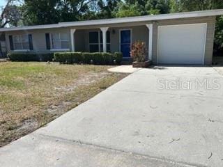 ranch-style house featuring a garage, concrete driveway, and a porch