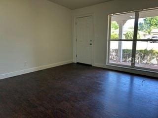 unfurnished room featuring baseboards and dark wood-style floors