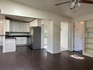 kitchen featuring dark countertops, freestanding refrigerator, a ceiling fan, white cabinetry, and a peninsula