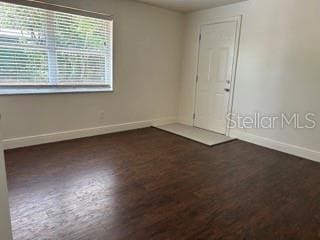 spare room with baseboards and wood finished floors