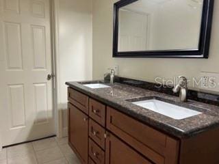 bathroom with double vanity, a sink, and tile patterned flooring