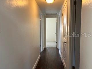 hall featuring baseboards and dark wood-type flooring