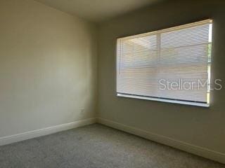 carpeted spare room featuring baseboards