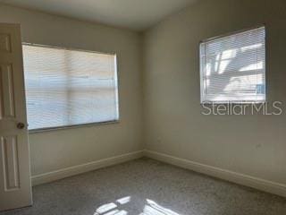 carpeted spare room featuring baseboards