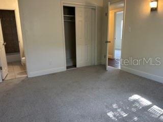 unfurnished bedroom with baseboards, connected bathroom, and a closet
