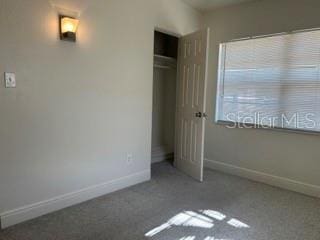 unfurnished bedroom featuring carpet floors, baseboards, and a closet