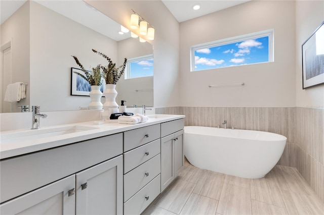 7905 Jacks Club Dr, Kissimmee, FL 34747 - full bathroom featuring tile walls, double vanity, a freestanding bath, wainscoting, and recessed lighting
