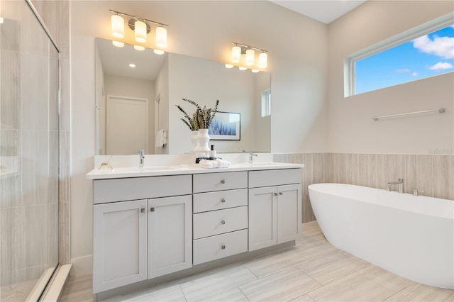 7905 Jacks Club Dr, Kissimmee, FL 34747 - bathroom featuring a stall shower, double vanity, a freestanding tub, tile walls, and wainscoting