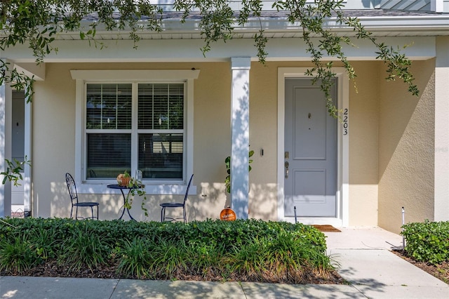 entrance to property featuring a porch and stucco siding