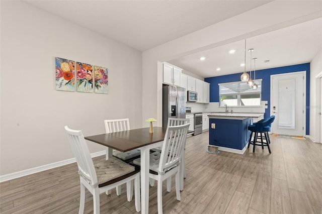 dining area featuring light wood finished floors, baseboards, and recessed lighting