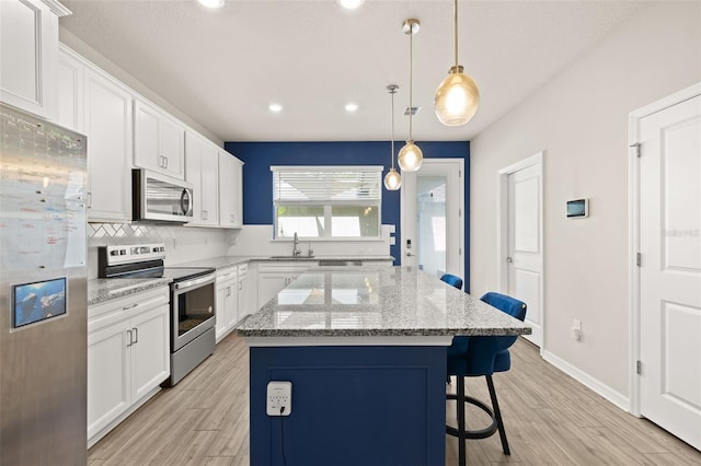 kitchen featuring stainless steel appliances, a kitchen breakfast bar, a center island, tasteful backsplash, and white cabinets