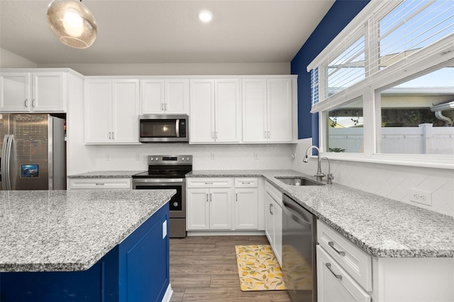 kitchen featuring appliances with stainless steel finishes, a sink, white cabinetry, and tasteful backsplash