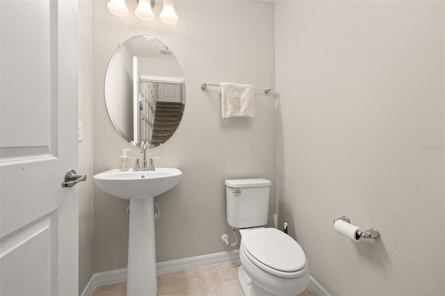 half bathroom with toilet, tile patterned floors, and baseboards