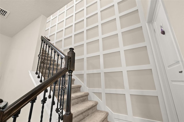 staircase featuring a textured ceiling