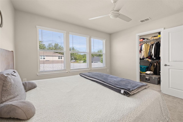 bedroom featuring a walk in closet, multiple windows, a closet, and light colored carpet