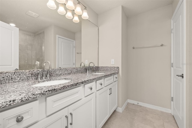 bathroom featuring double vanity, baseboards, and tiled shower