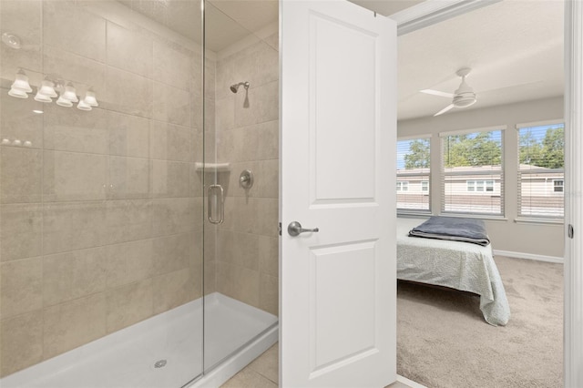 ensuite bathroom featuring a shower stall, a ceiling fan, and baseboards