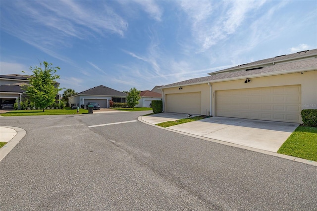 view of front of home with stucco siding, a garage, a residential view, and concrete driveway