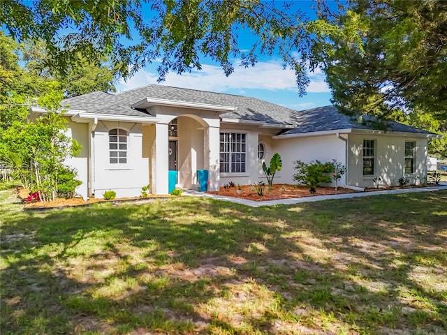 view of front of home with a shingled roof, stucco siding, and a front yard