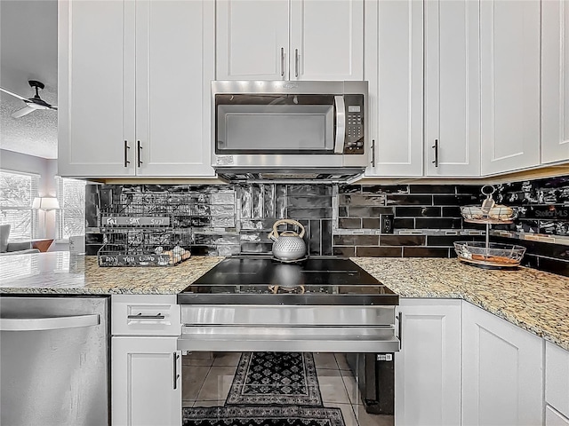 kitchen with appliances with stainless steel finishes, decorative backsplash, light stone counters, and white cabinets