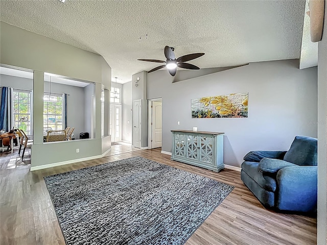 living area featuring a ceiling fan, a textured ceiling, lofted ceiling, and wood finished floors