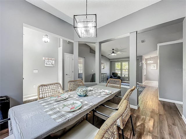 dining room featuring baseboards, visible vents, wood finished floors, and ceiling fan with notable chandelier