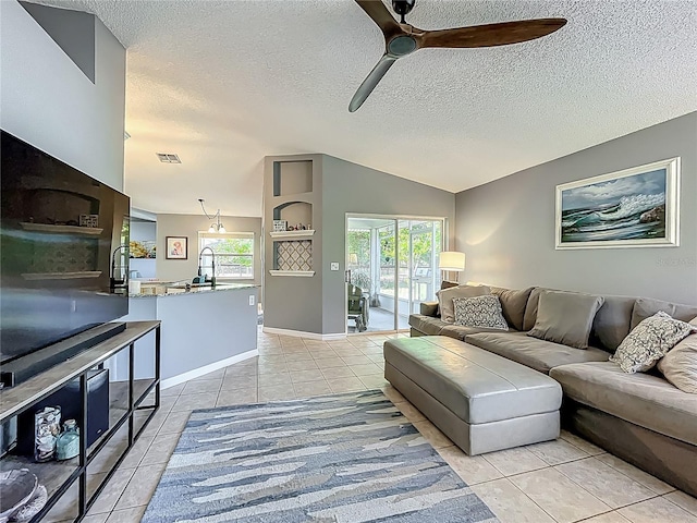 living area with light tile patterned floors, a ceiling fan, a textured ceiling, and visible vents