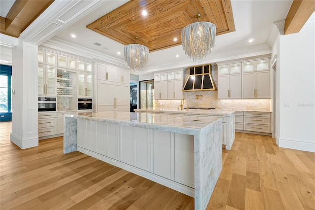 5525 Isleworth Country Club Dr, Windermere, FL 34786 - kitchen featuring a tray ceiling, a spacious island, appliances with stainless steel finishes, backsplash, and light wood-style floors