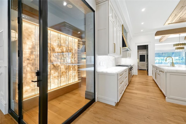 5525 Isleworth Country Club Dr, Windermere, FL 34786 - kitchen featuring high end range, crown molding, white cabinetry, a sink, and light wood-type flooring