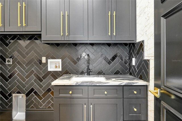 5525 Isleworth Country Club Dr, Windermere, FL 34786 - kitchen with gray cabinets, light stone counters, decorative backsplash, and a sink