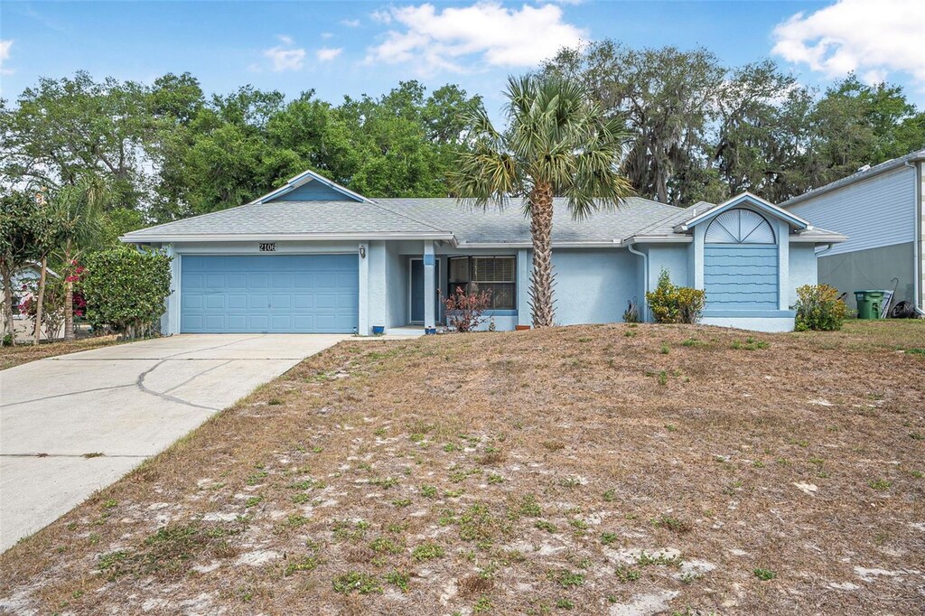 ranch-style home with concrete driveway, an attached garage, a shingled roof, and stucco siding
