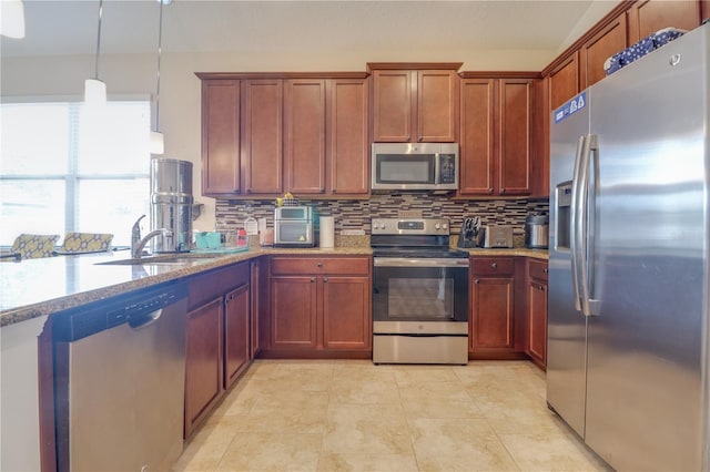kitchen with brown cabinets, light stone counters, a sink, appliances with stainless steel finishes, and backsplash