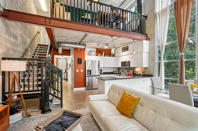living room with baseboards, stairway, and finished concrete flooring