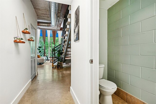 bathroom featuring baseboards, concrete floors, and toilet