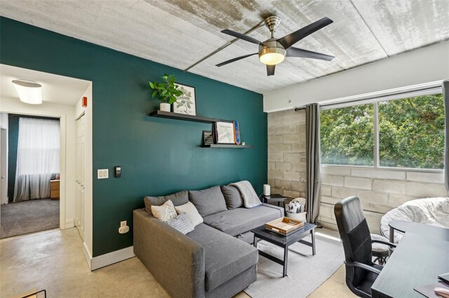 office area featuring a ceiling fan, baseboards, concrete flooring, and a wealth of natural light
