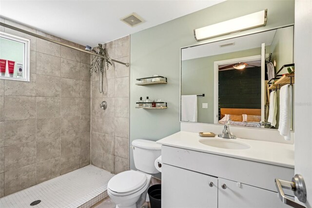full bathroom featuring toilet, visible vents, tiled shower, and vanity