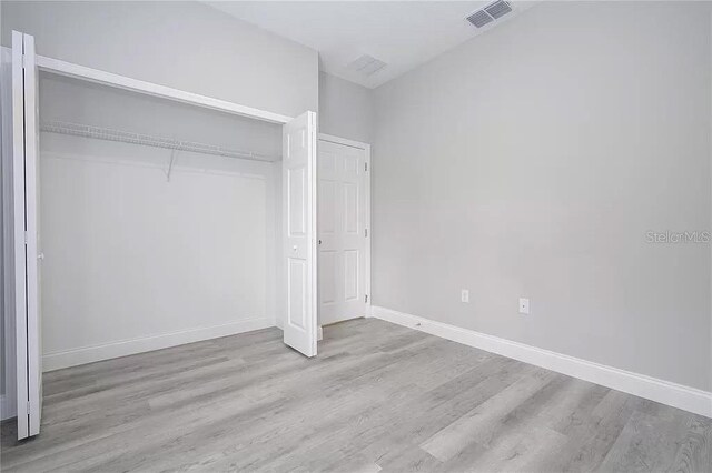 8312 N Pitcairn Way, Citrus Springs, FL 34434 - unfurnished bedroom with wood finished floors, baseboards, and a closet