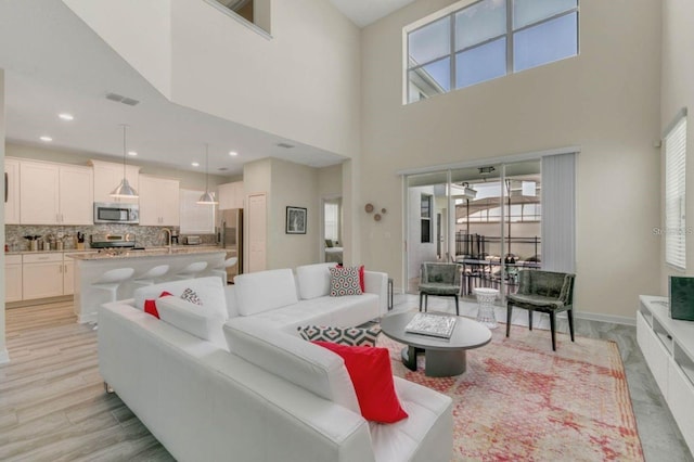 living room with a healthy amount of sunlight, a high ceiling, recessed lighting, and visible vents