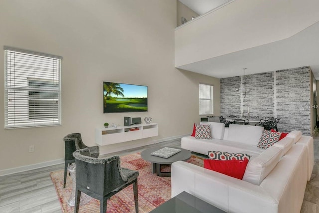 living area with baseboards, a high ceiling, and wood finished floors