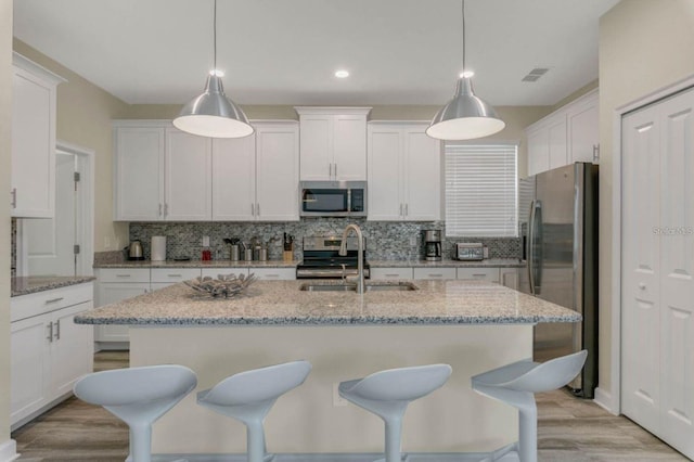 kitchen with a sink, appliances with stainless steel finishes, white cabinets, and tasteful backsplash