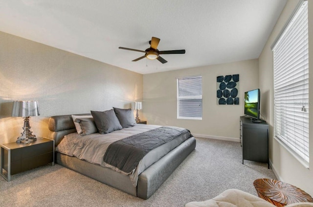 bedroom with baseboards, multiple windows, light carpet, and a ceiling fan