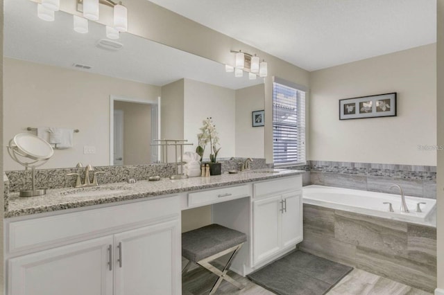 bathroom with a garden tub, a sink, wood finished floors, and double vanity