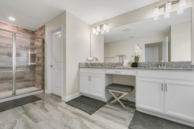 full bath featuring baseboards, double vanity, a sink, and a shower stall