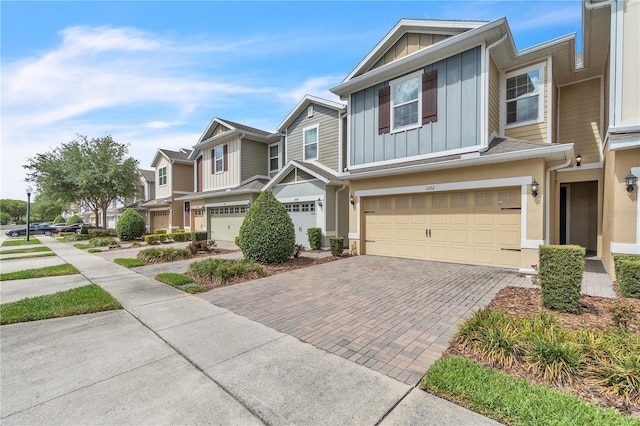 multi unit property featuring a residential view, board and batten siding, an attached garage, and decorative driveway