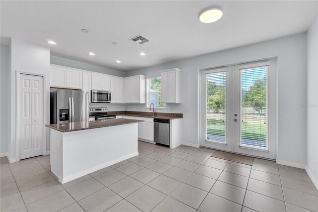 kitchen featuring a sink, dark stone counters, stainless steel appliances, baseboards, and visible vents