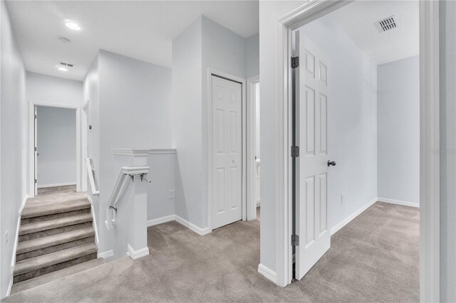 corridor featuring visible vents, carpet, and baseboards