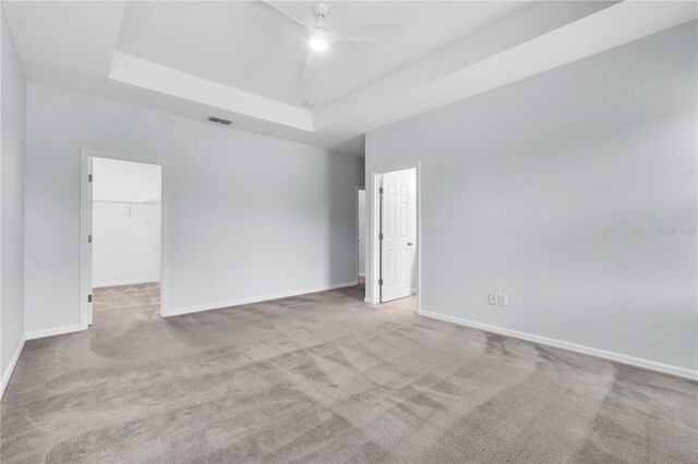 carpeted empty room featuring baseboards, a tray ceiling, and visible vents